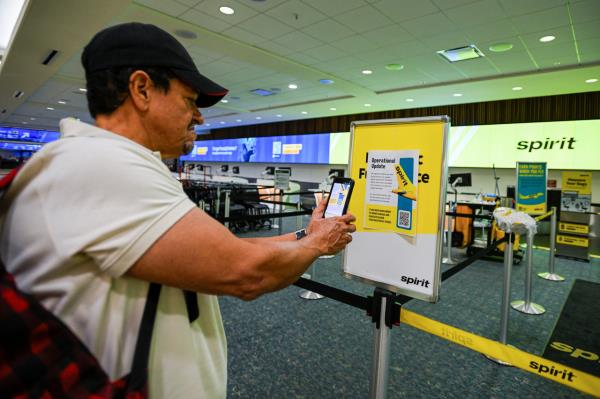 A passenger takes a photograph of a Spirit Airlines operational update notice at Orlando International Airport in Orlando, Florida, Saturday.   Reuters-Yonhap