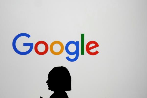 A woman walks past a giant screen displaying a logo at the Paris Google Lab during the AI Action Summit in Paris in February 2025. (AP-Yonhap)